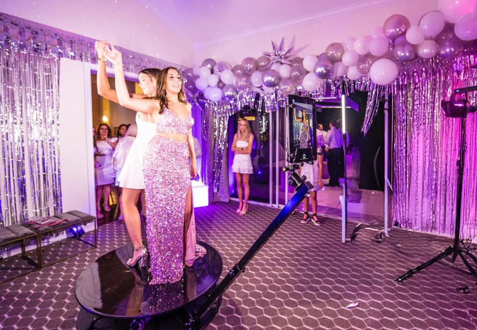A group of people, having fun at a party with balloons and lights, pose for a photo in our 360 degree photobooth.